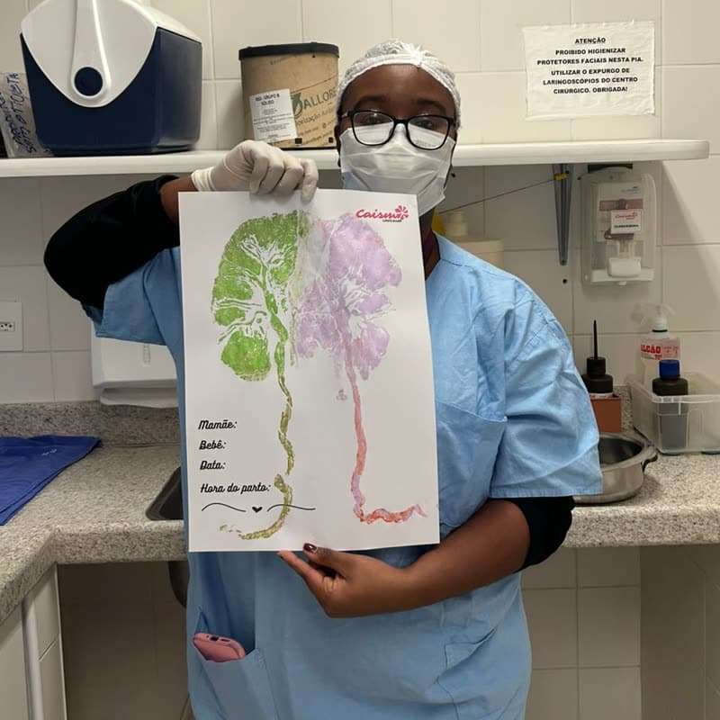 Mariana segurando o registro artístico de uma placenta, com espaço para o nome da mãe, do bebê e a hora do parto